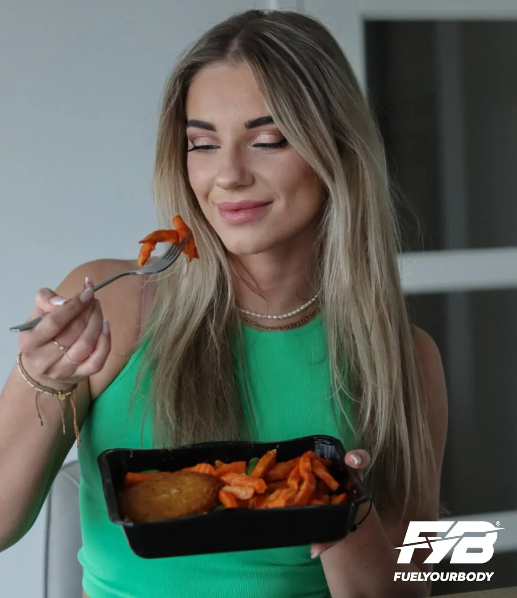 Vrouw geniet van een zoete aardappel kipburger maaltijd